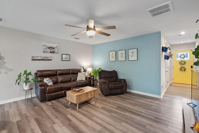 living room featuring light wood-type flooring, visible vents, and baseboards