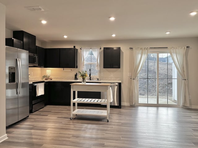 kitchen featuring light countertops, visible vents, appliances with stainless steel finishes, dark cabinetry, and plenty of natural light