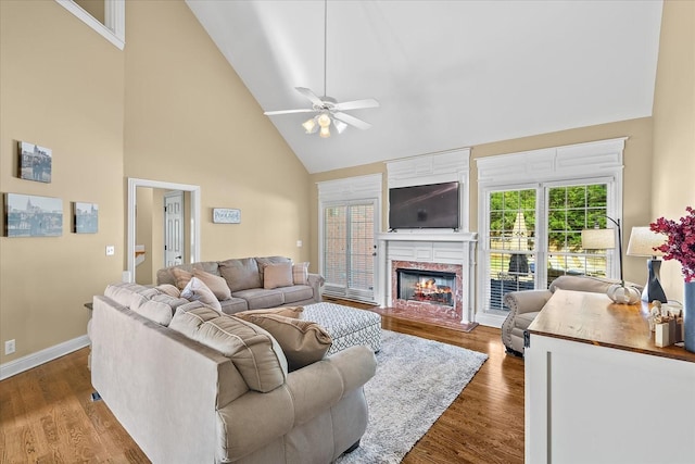 living room featuring ceiling fan, dark wood-type flooring, high vaulted ceiling, and a premium fireplace