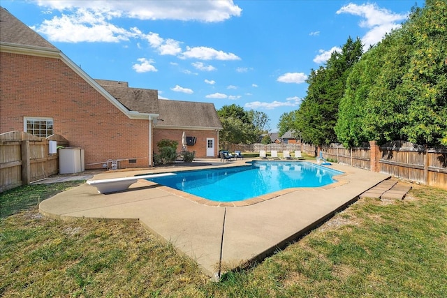 view of swimming pool featuring a patio area, a yard, and a diving board