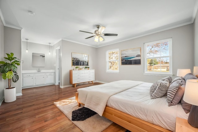 bedroom with baseboards, ensuite bath, wood finished floors, crown molding, and a sink