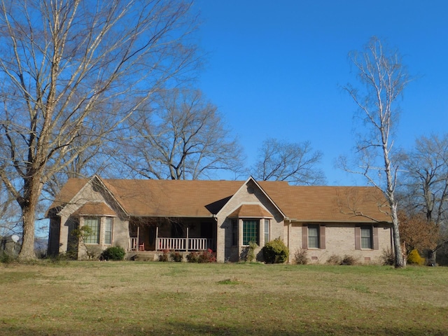 ranch-style home featuring covered porch and a front lawn