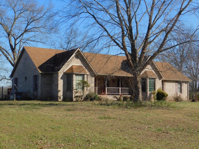 ranch-style house featuring covered porch and a front lawn