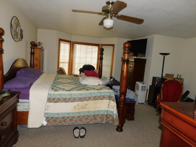 carpeted bedroom with ceiling fan and a textured ceiling