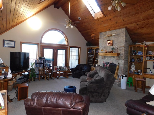 living room featuring ceiling fan, carpet flooring, a fireplace, high vaulted ceiling, and a skylight