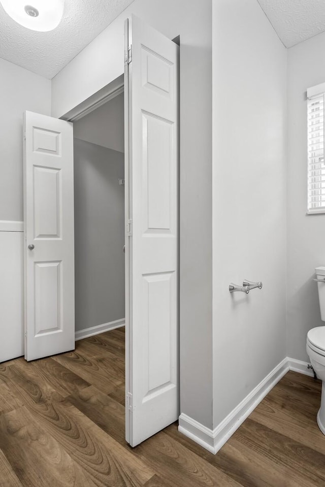 bathroom featuring toilet, a textured ceiling, and hardwood / wood-style flooring