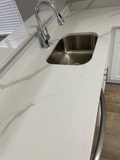 details with white cabinets, sink, and light stone counters