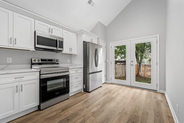 kitchen with appliances with stainless steel finishes, white cabinetry, french doors, light hardwood / wood-style floors, and high vaulted ceiling