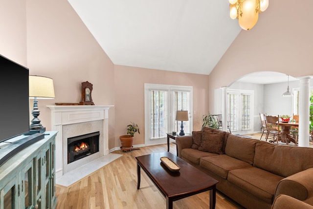 living room with vaulted ceiling, a high end fireplace, ornate columns, and light wood-type flooring