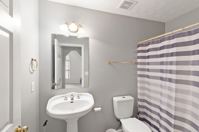 bathroom with sink, a textured ceiling, toilet, and a shower with curtain