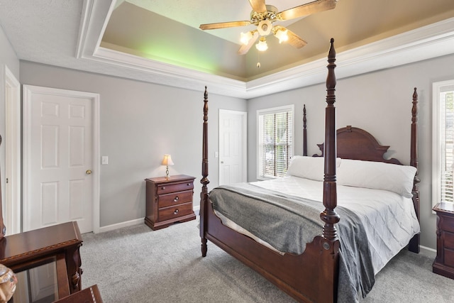 carpeted bedroom with ceiling fan and a tray ceiling