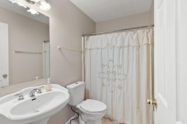 bathroom with toilet, sink, a textured ceiling, and curtained shower