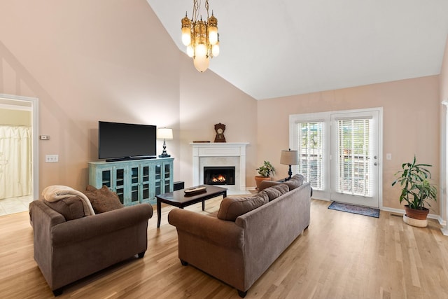 living room featuring an inviting chandelier, light hardwood / wood-style floors, and high vaulted ceiling