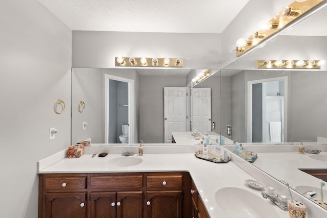 bathroom featuring toilet, vanity, and a textured ceiling