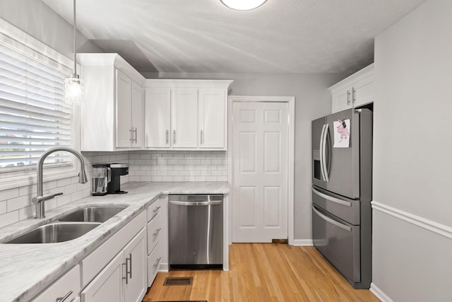 kitchen with sink, hanging light fixtures, white cabinets, and stainless steel appliances