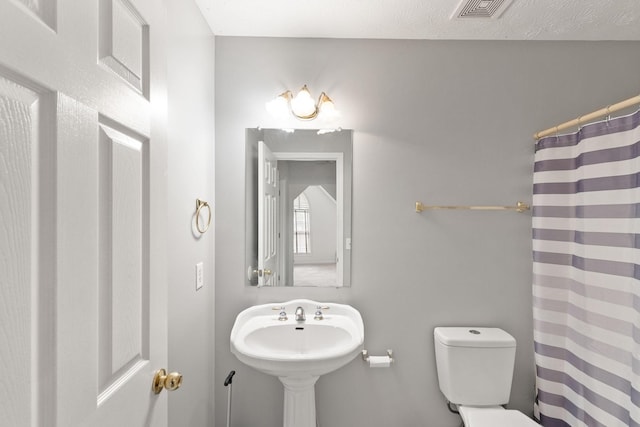 bathroom with sink, a textured ceiling, toilet, and walk in shower