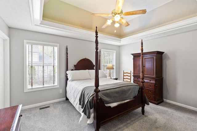 bedroom with ceiling fan, a tray ceiling, and light carpet