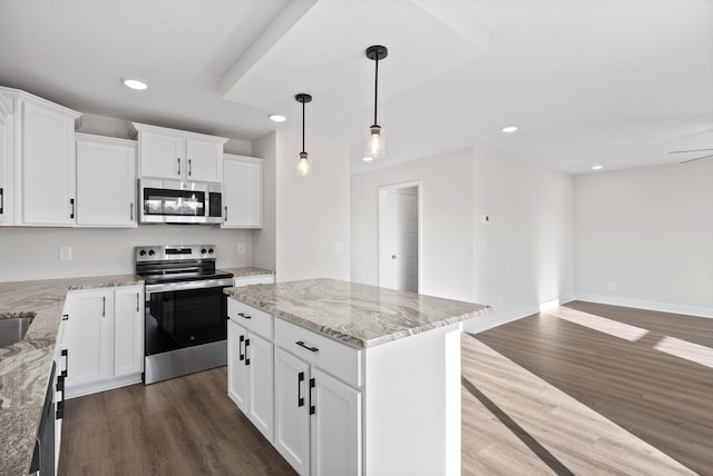 kitchen featuring a center island, light stone counters, stainless steel appliances, and white cabinetry