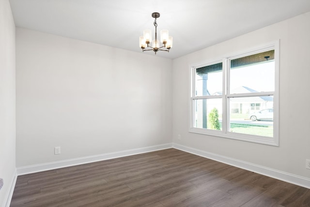 spare room featuring dark hardwood / wood-style floors and an inviting chandelier