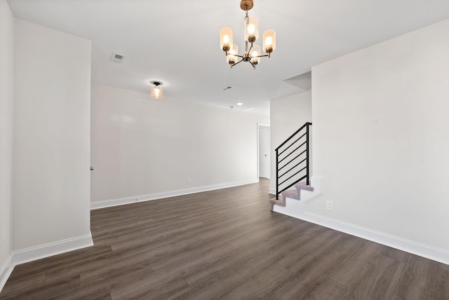 spare room with dark hardwood / wood-style flooring and a chandelier