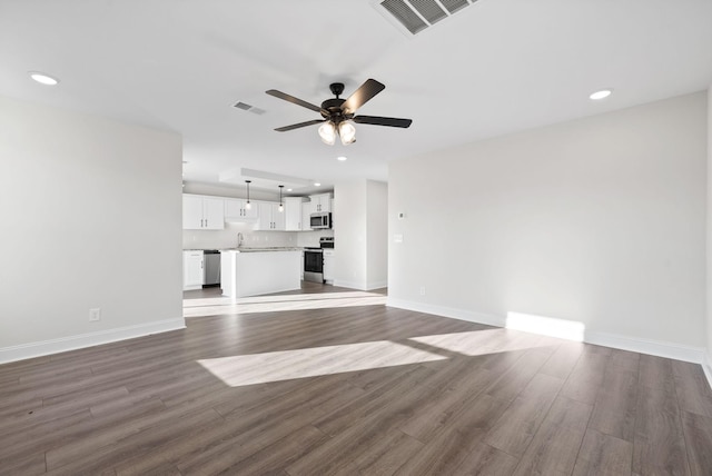 unfurnished living room featuring ceiling fan, sink, and dark hardwood / wood-style floors