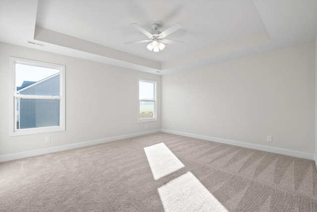 carpeted spare room featuring ceiling fan and a tray ceiling