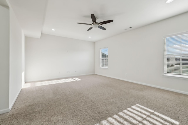 empty room featuring ceiling fan, a healthy amount of sunlight, and light colored carpet