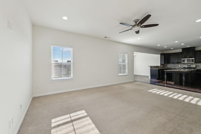 unfurnished living room featuring ceiling fan and carpet