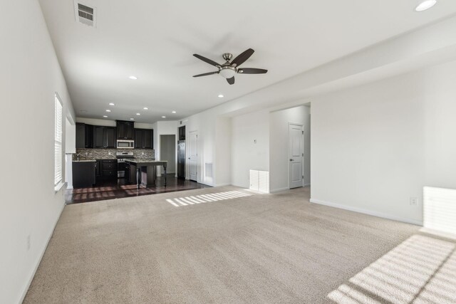 unfurnished living room featuring ceiling fan and dark carpet