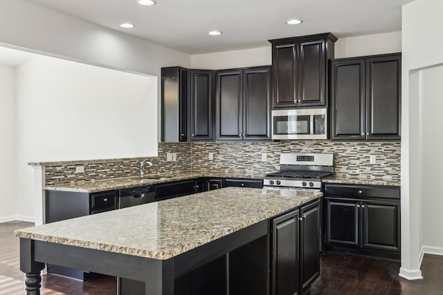 kitchen featuring stainless steel appliances, dark hardwood / wood-style floors, tasteful backsplash, light stone countertops, and sink