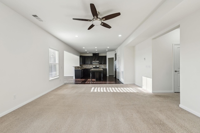 unfurnished living room with ceiling fan and carpet