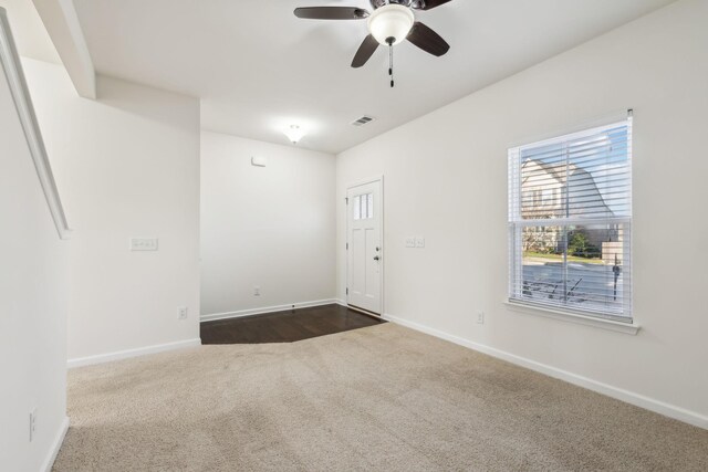 unfurnished room with ceiling fan and dark colored carpet