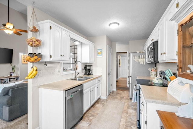 kitchen featuring a textured ceiling, white cabinetry, stainless steel appliances, sink, and ceiling fan