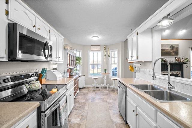 kitchen featuring appliances with stainless steel finishes, decorative backsplash, a textured ceiling, white cabinets, and sink