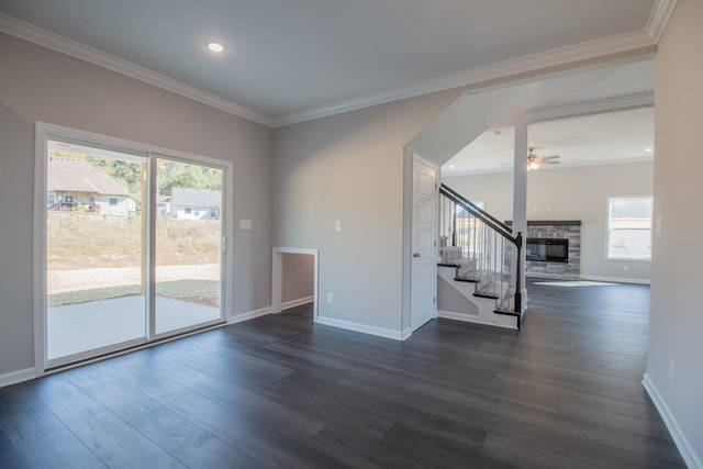 interior space with ceiling fan, dark hardwood / wood-style floors, crown molding, and a stone fireplace