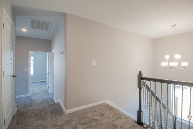 hallway featuring carpet floors, plenty of natural light, and an inviting chandelier