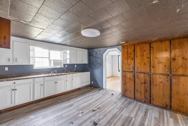 kitchen with light hardwood / wood-style flooring, white cabinets, and sink