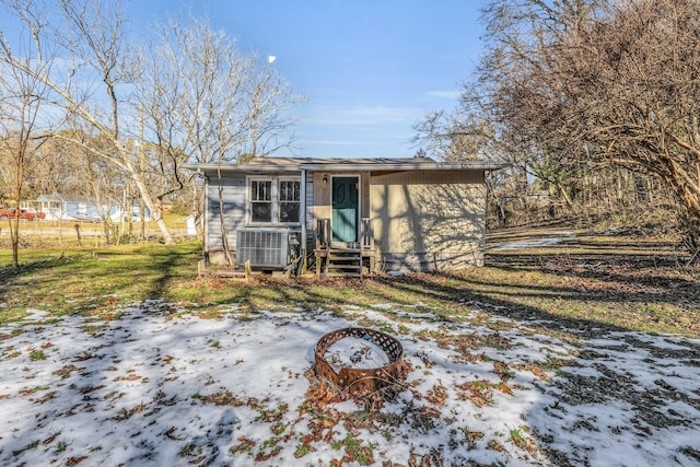 exterior space with central air condition unit, an outdoor fire pit, and a yard