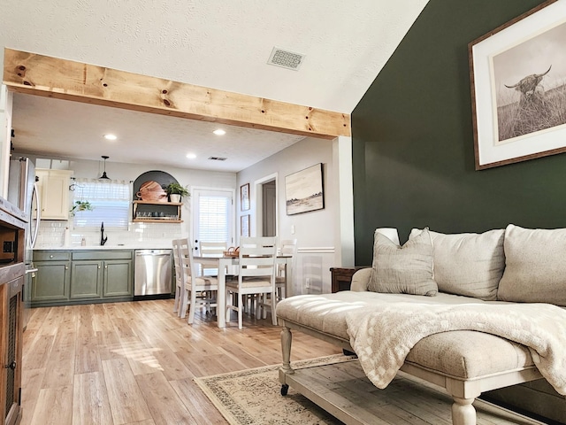 living room featuring sink, beamed ceiling, and light hardwood / wood-style floors