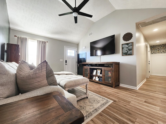 living room with light wood-type flooring, ceiling fan, lofted ceiling, and a textured ceiling