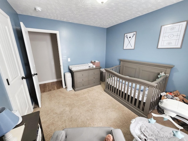 bedroom with a textured ceiling, light carpet, and a crib