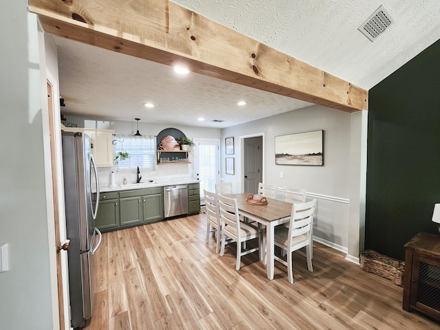 dining area with light hardwood / wood-style floors, sink, and a textured ceiling