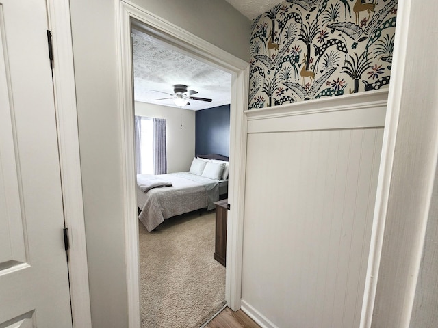 bedroom with ceiling fan, carpet floors, and a textured ceiling