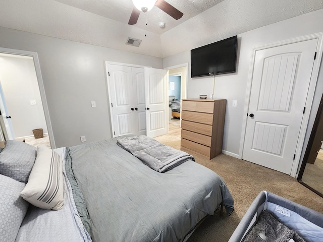 carpeted bedroom with ceiling fan, a textured ceiling, a closet, and lofted ceiling