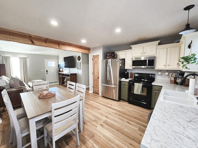 kitchen featuring pendant lighting, appliances with stainless steel finishes, beamed ceiling, sink, and backsplash