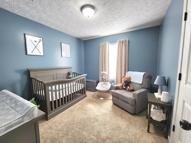 carpeted bedroom with a crib and a textured ceiling