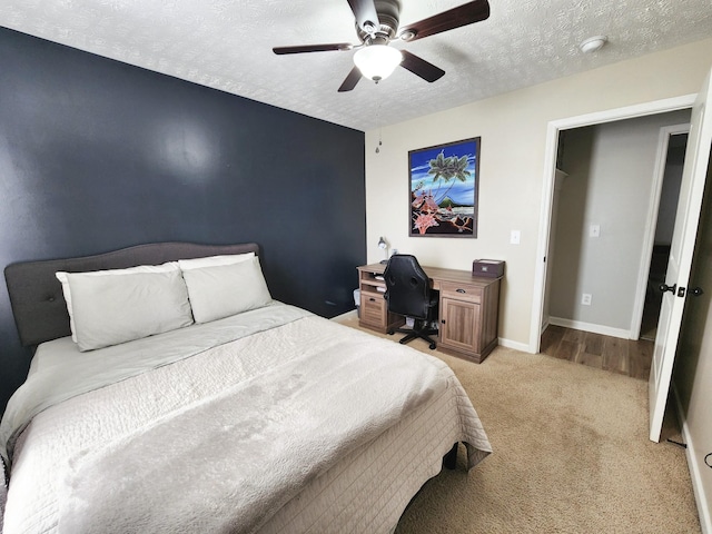 bedroom featuring ceiling fan, light colored carpet, and a textured ceiling