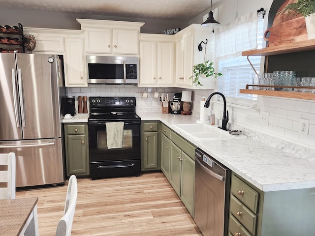 kitchen with appliances with stainless steel finishes, decorative backsplash, light wood-type flooring, pendant lighting, and sink