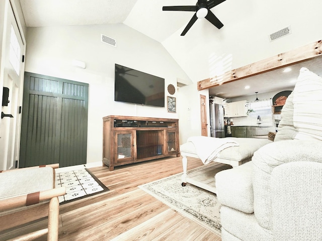 living room with light wood-type flooring, ceiling fan, and high vaulted ceiling