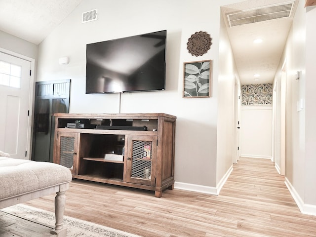 living room with light hardwood / wood-style floors and vaulted ceiling